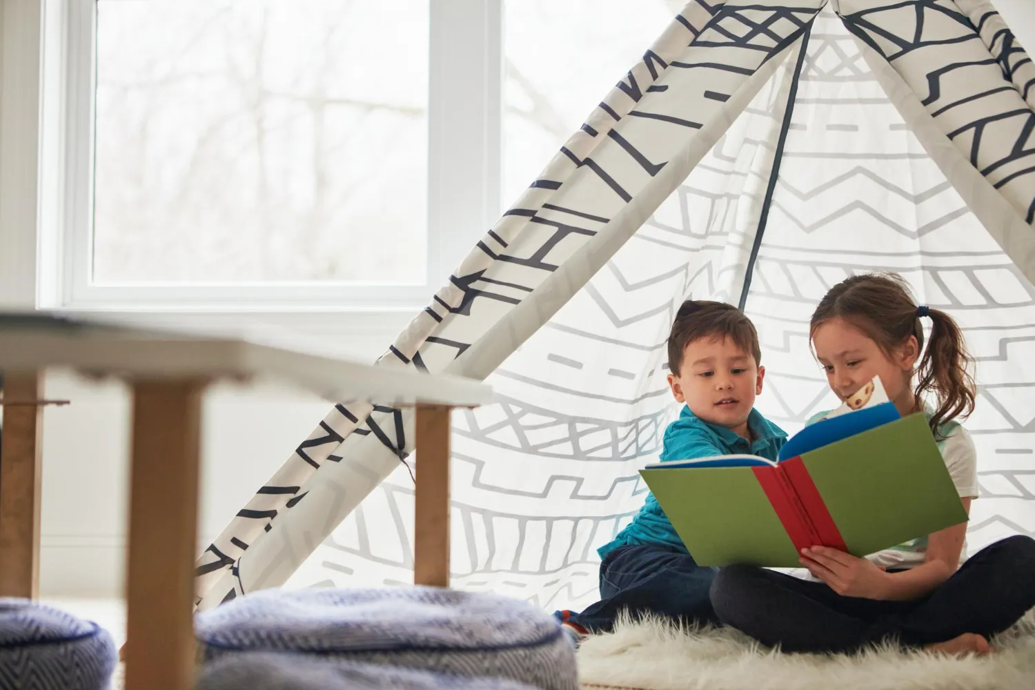 des enfants sont en train de lire des livres sous un tipi