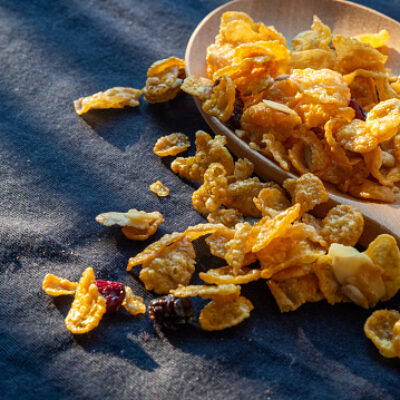 Cornflakes and  mix cairns is breakfast food in the wood spoon on black cloth with natural light.